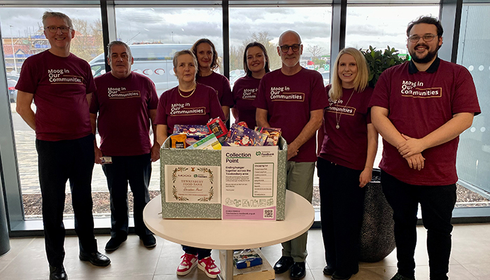 Moog employees standing behind donation box